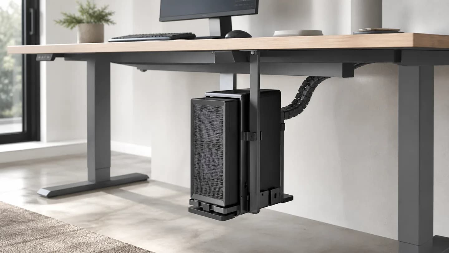 Editorial sit-stand desk underside with an adjustable CPU holder, desktop computer case, airflow arrows, cable loop, mounting plate, and knee clearance